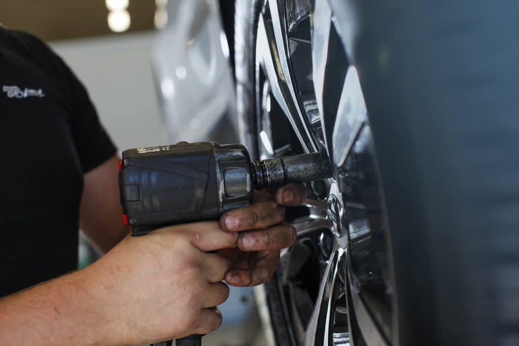 Tekniker skruvar ur bultar för att byta däck på en bil.