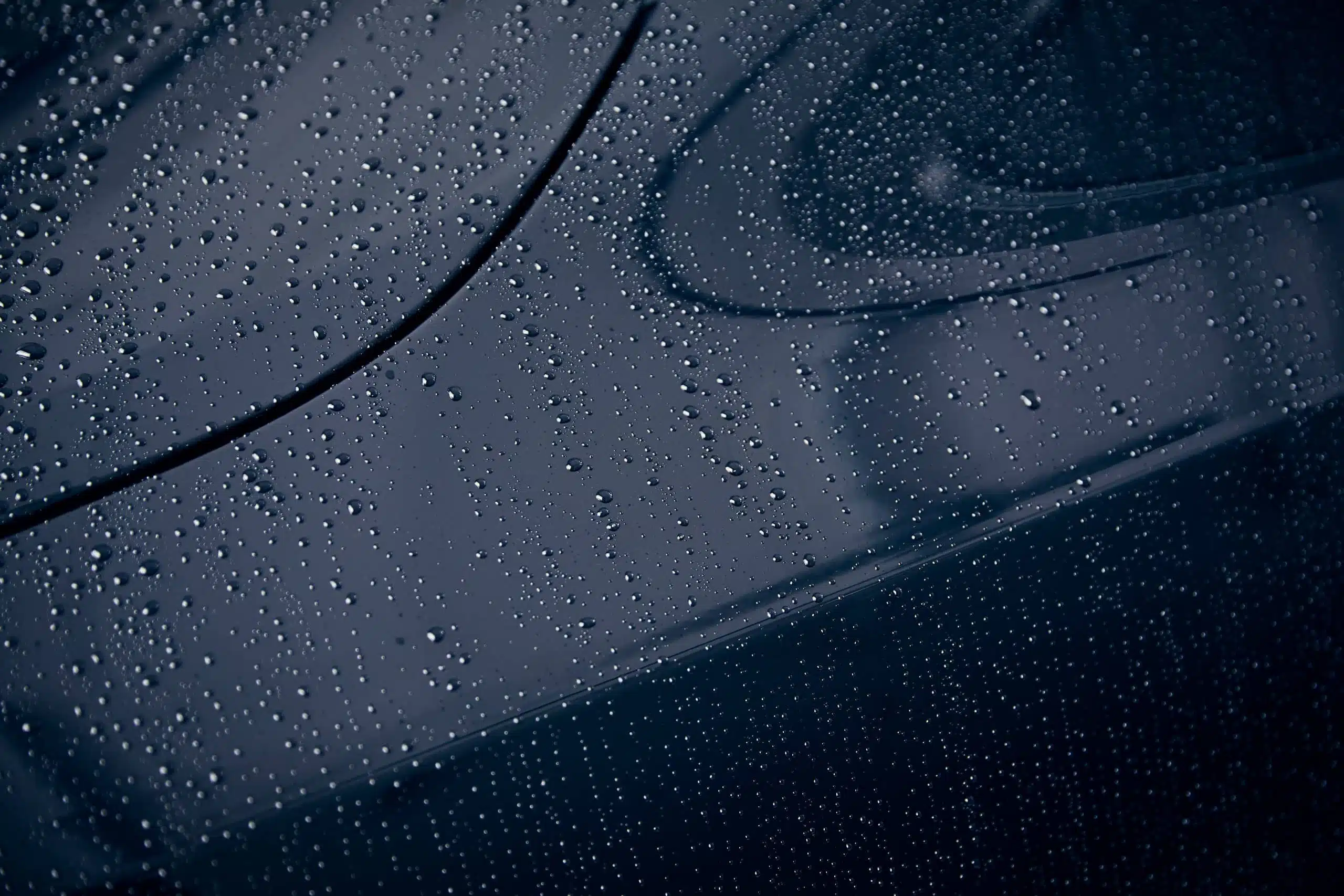 Närbild på vattendroppar på svartlackerad bil