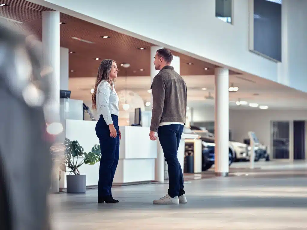 Kund tittar på begagnad bil i en bilhall hos en bilhandlare. 