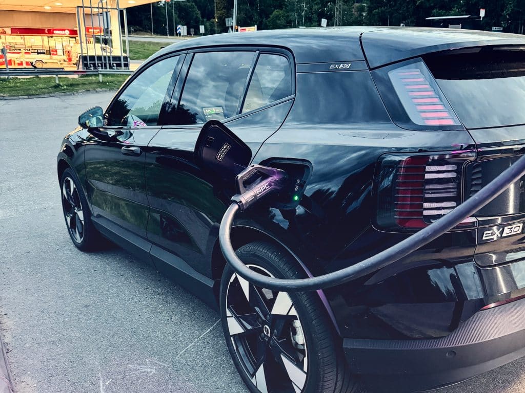 En svart bil snabbladdar el vid en laddstation.