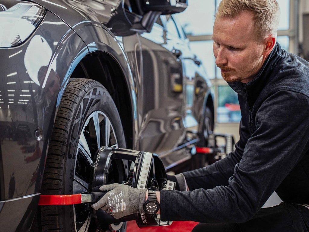 En tekniker genomför en hjulinställningen på en bil i verkstadsmiljö. 